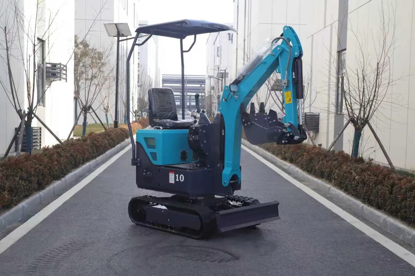 Blue canopy excavator with lowered bucket and tracks, front three-quarter view