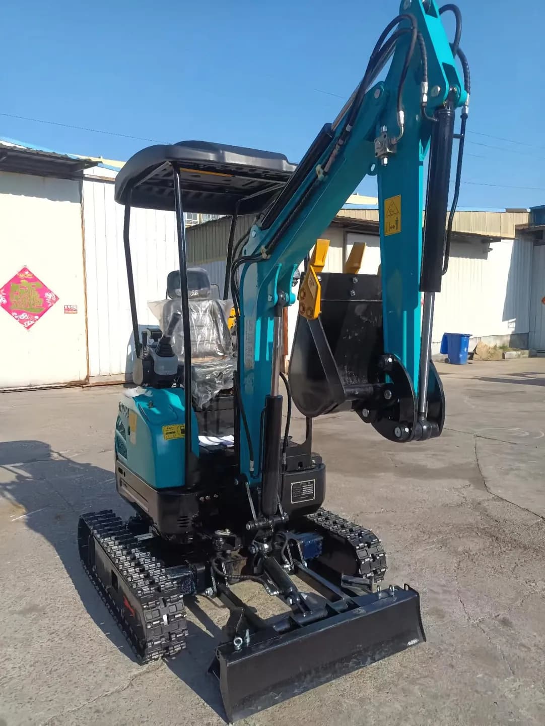 Blue tracked excavator with upright boom and front blade, front three-quarter view