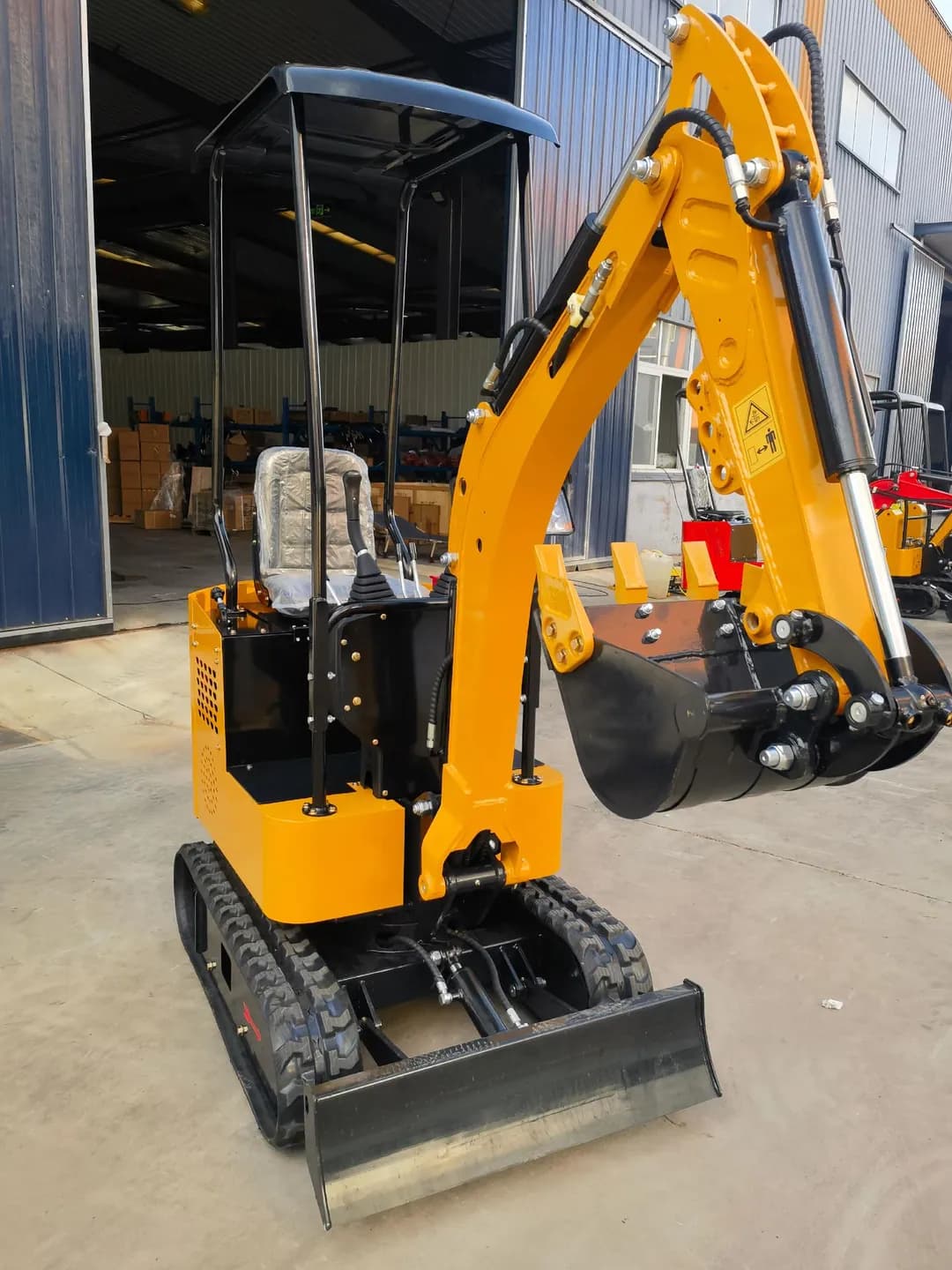 Yellow tracked excavator with canopy and bucket folded inward, front view