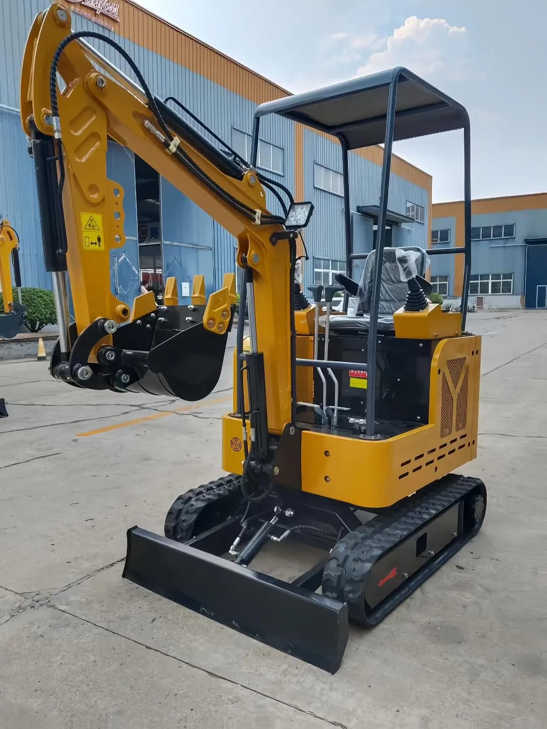 Yellow canopy excavator with raised bucket and front blade