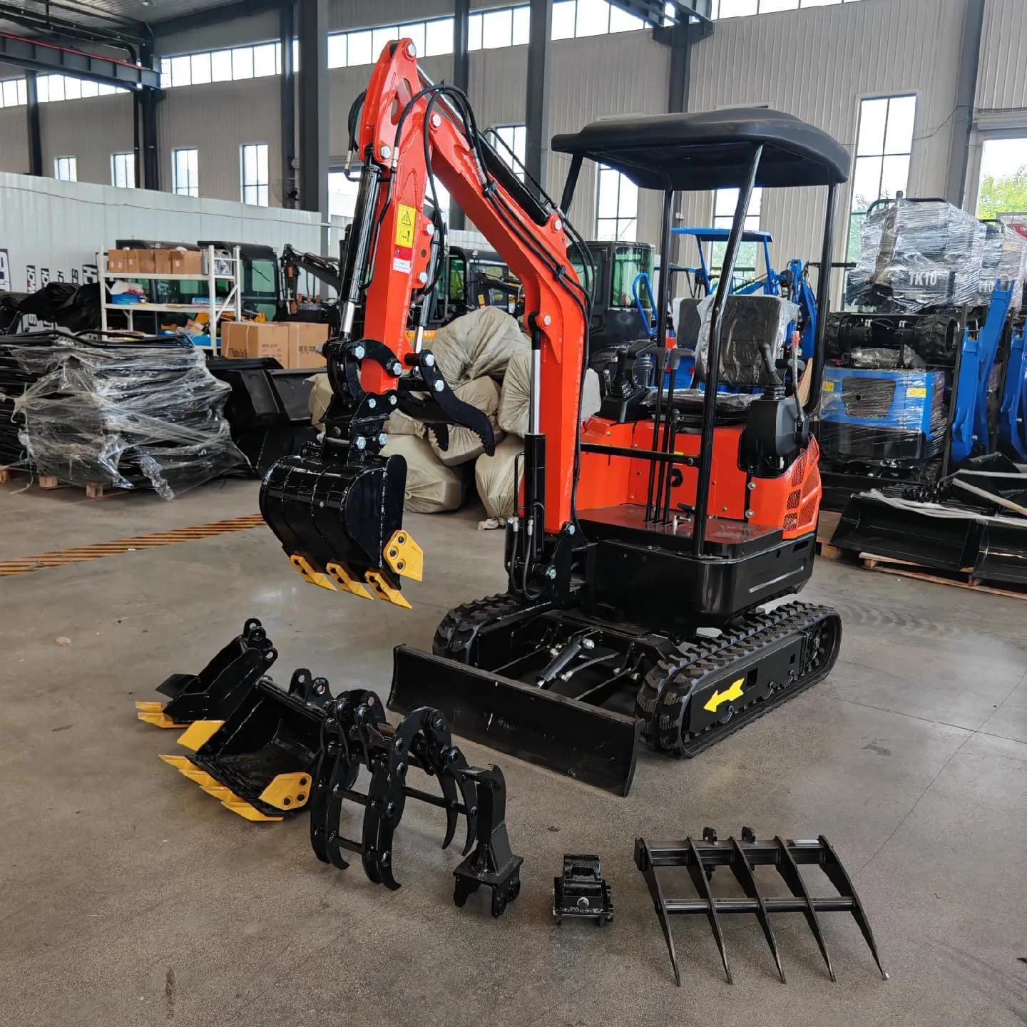 Red canopy excavator displayed with several attachments