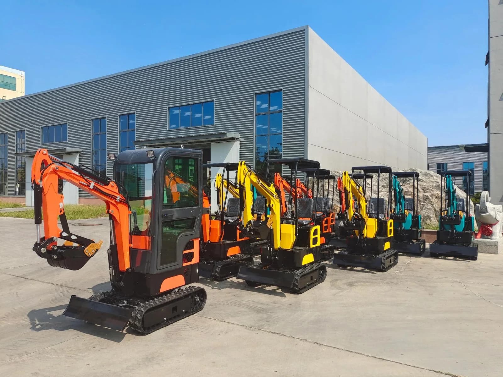 Compact excavators lined up with booms, buckets and tracked chassis visible