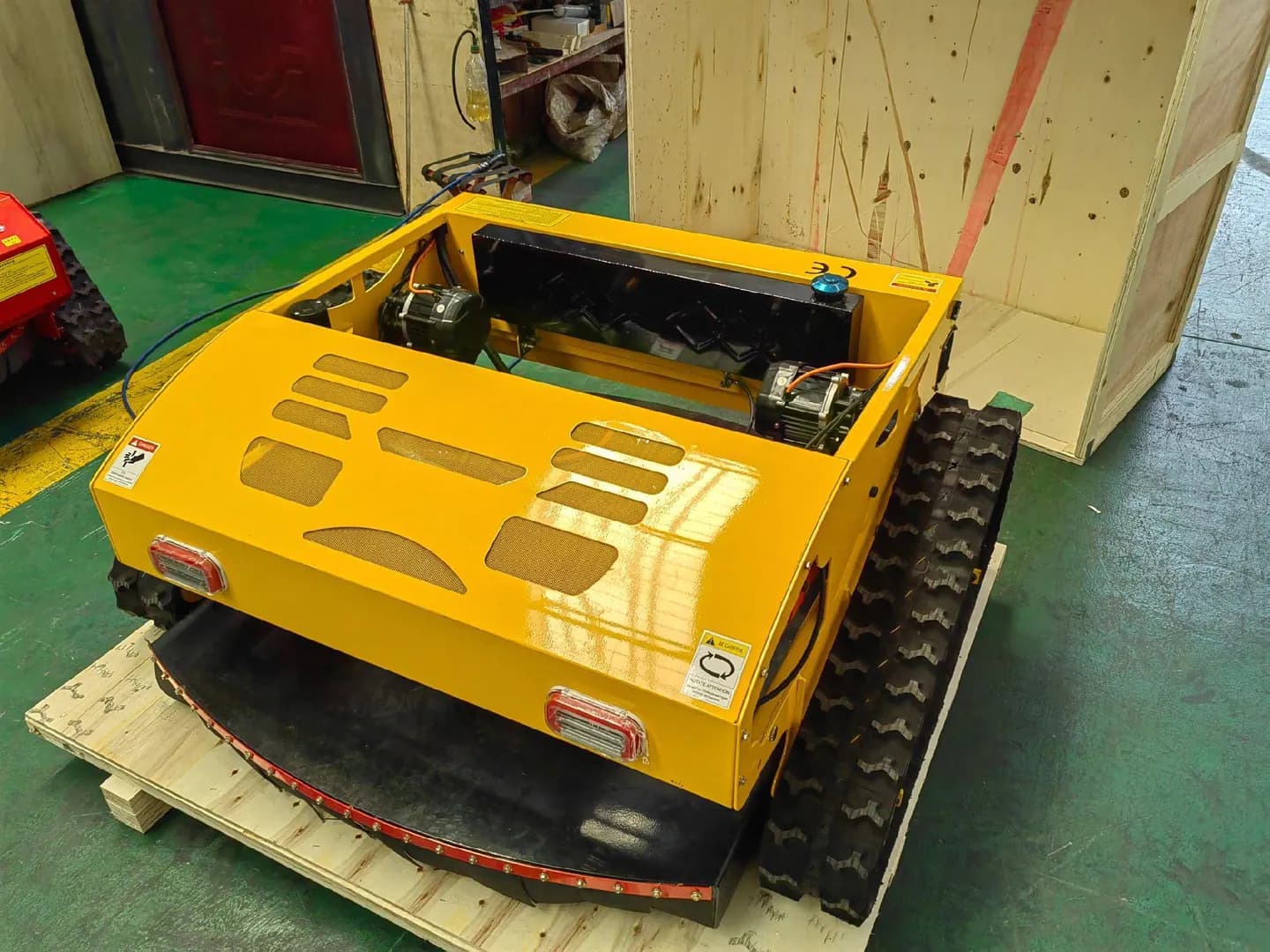 Yellow covered tracked mower with its full chassis visible, front three-quarter view