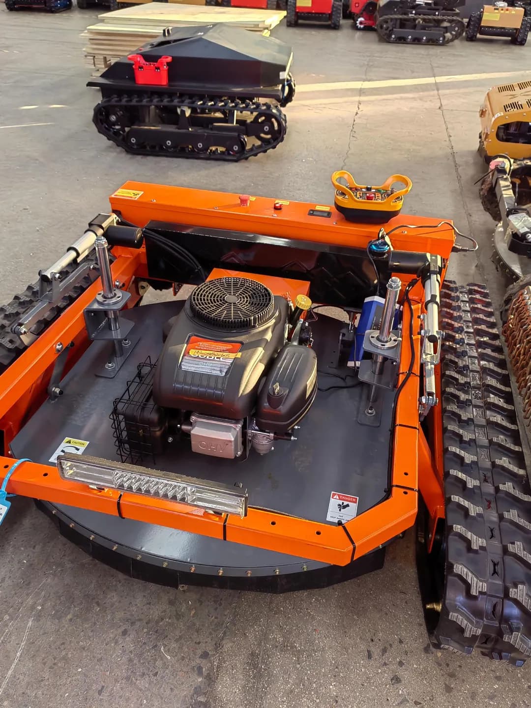 Orange tracked mower showing its engine, chain curtain and body cover from above