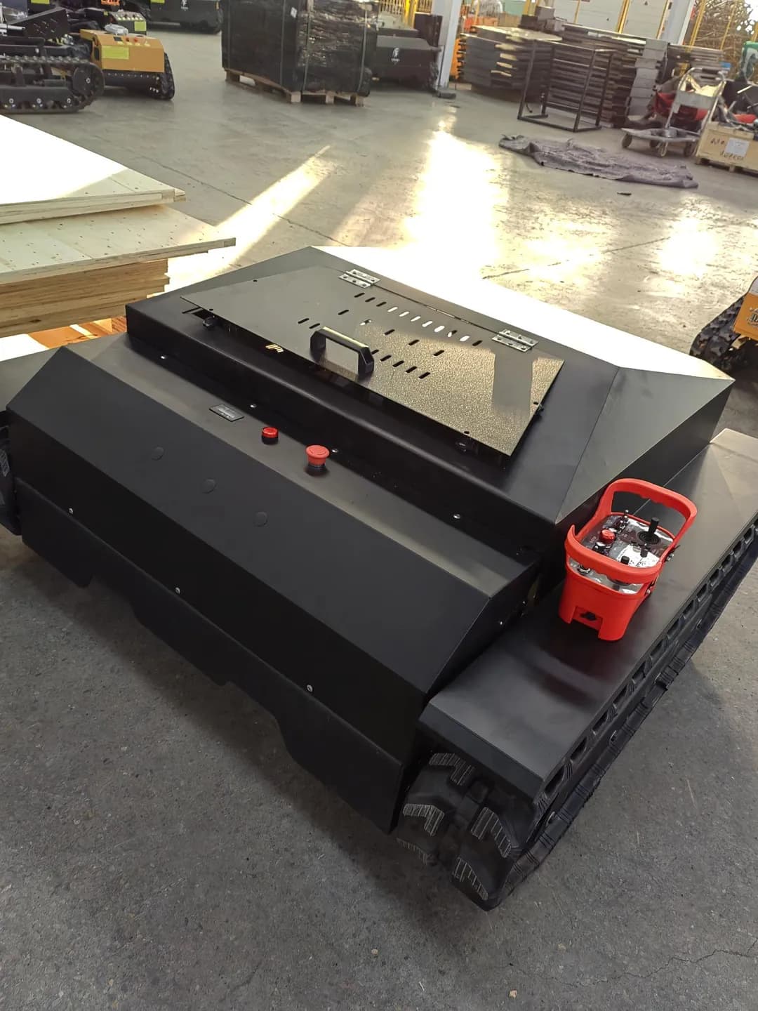 Black wide covered tracked mower showing its body and chassis, front three-quarter view