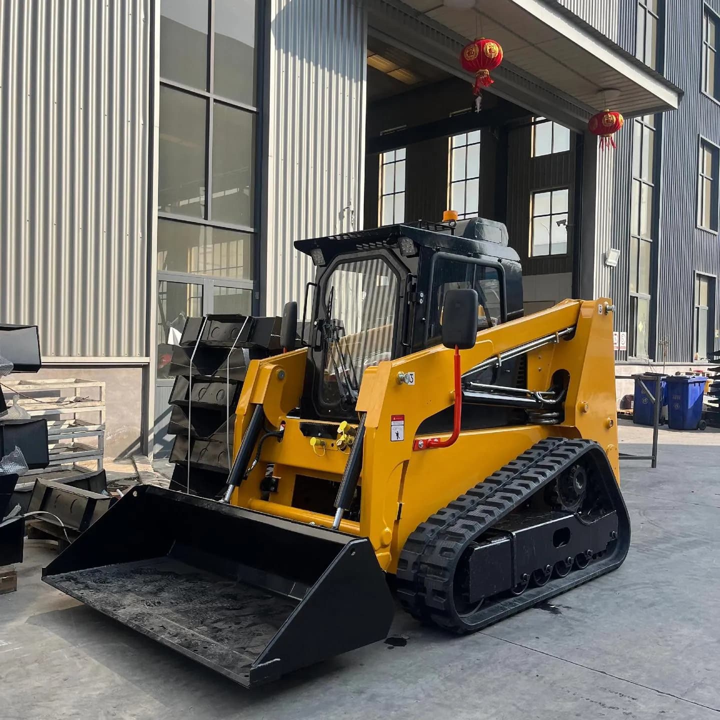 Yellow seated tracked loader showing its bucket and track assembly, front three-quarter view
