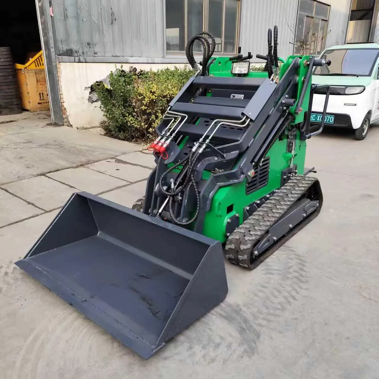 Green tracked loader with bucket and open stand-on operator area, front view