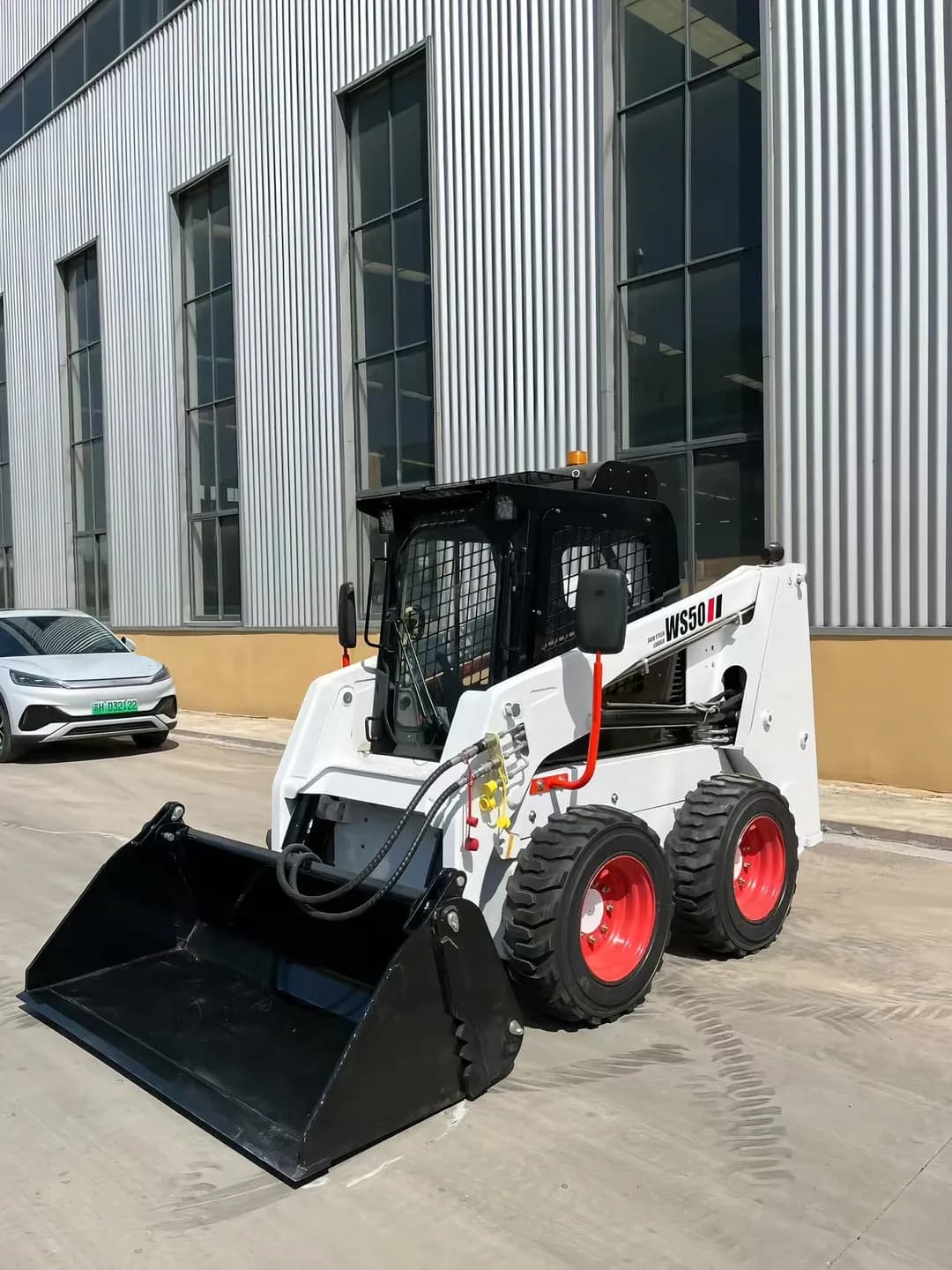 White and red wheeled loader with operator cage and bucket, front three-quarter view