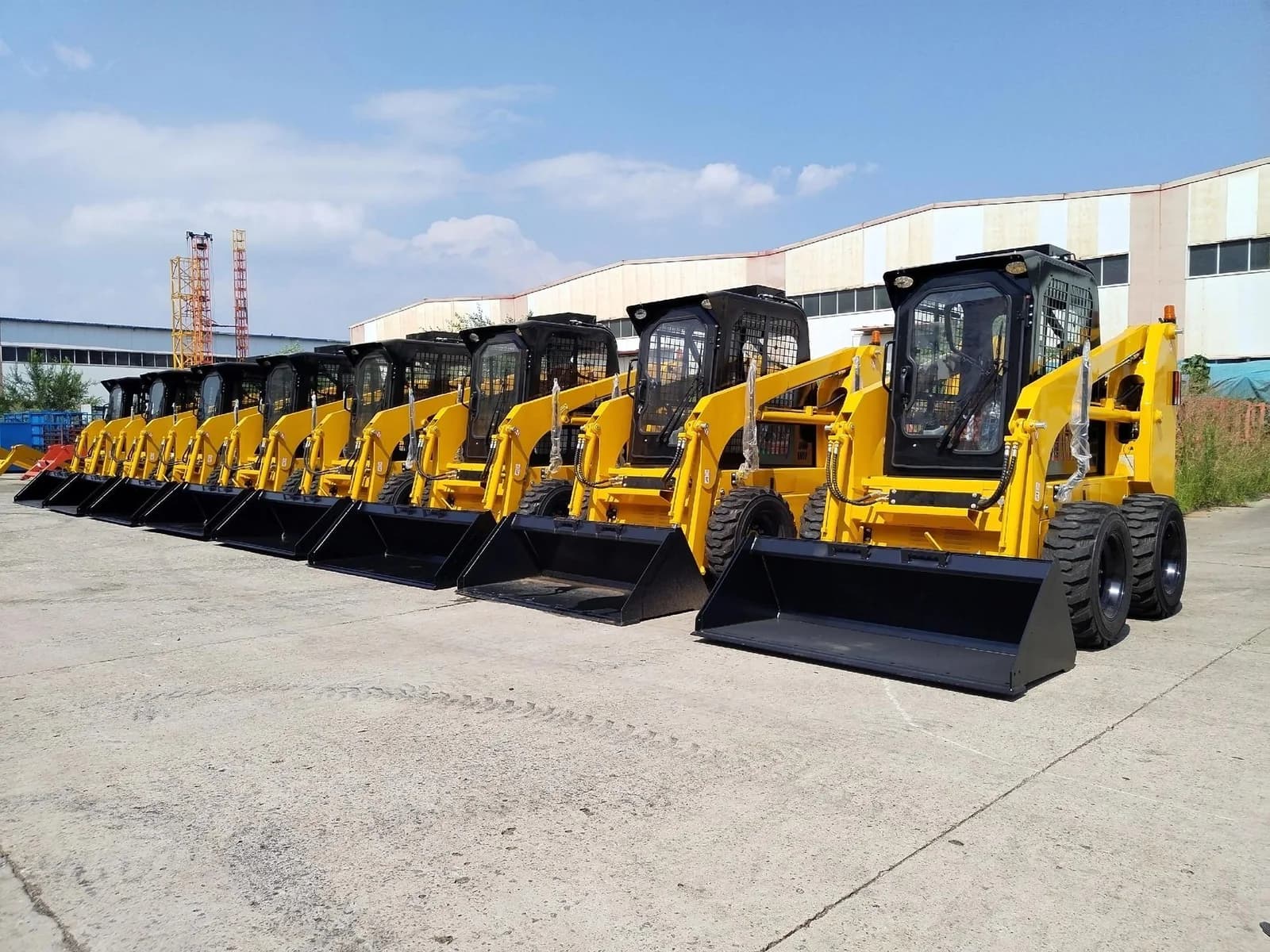 Wheeled skid steer loaders lined up with the front machine’s cab, lift arms and bucket visible