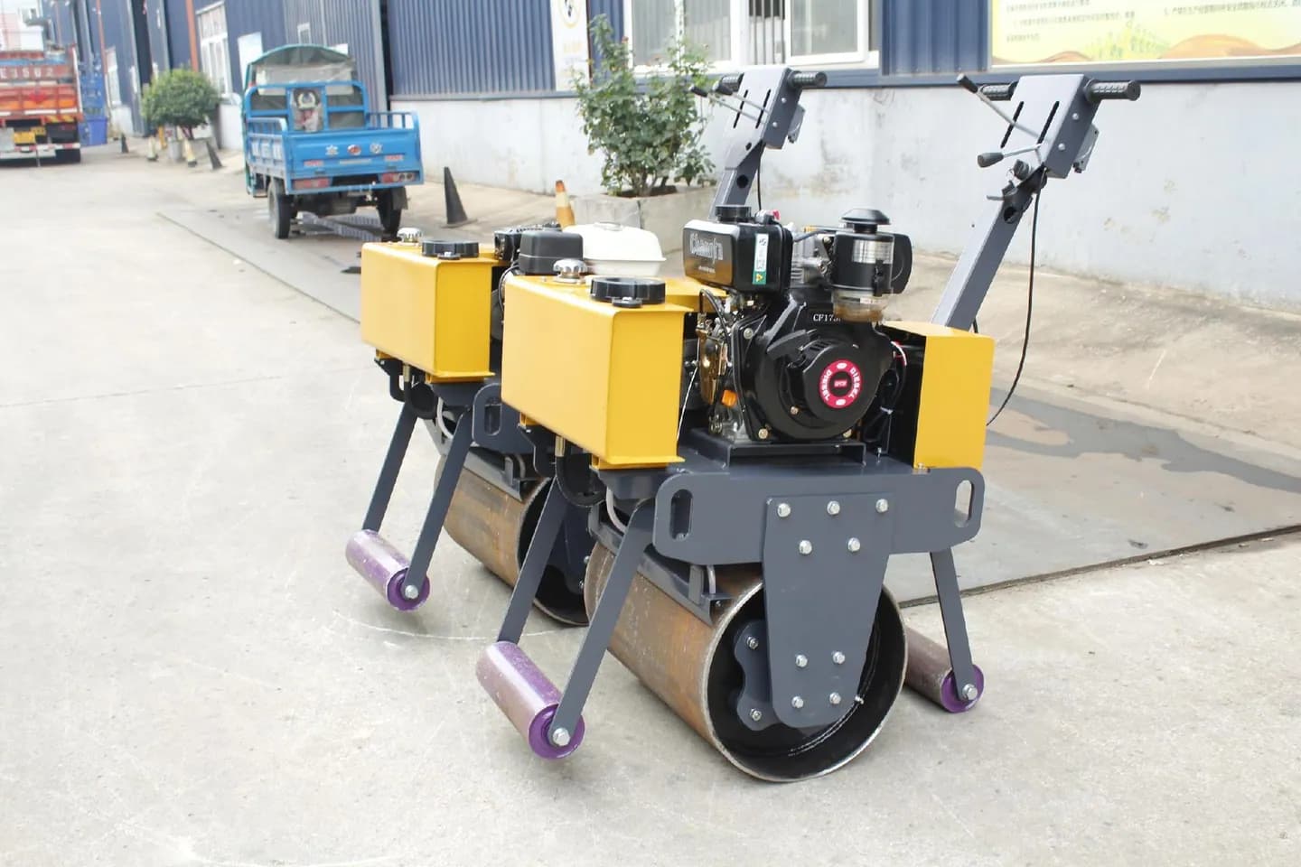 Walk-behind single-drum roller with small support wheels, front three-quarter view