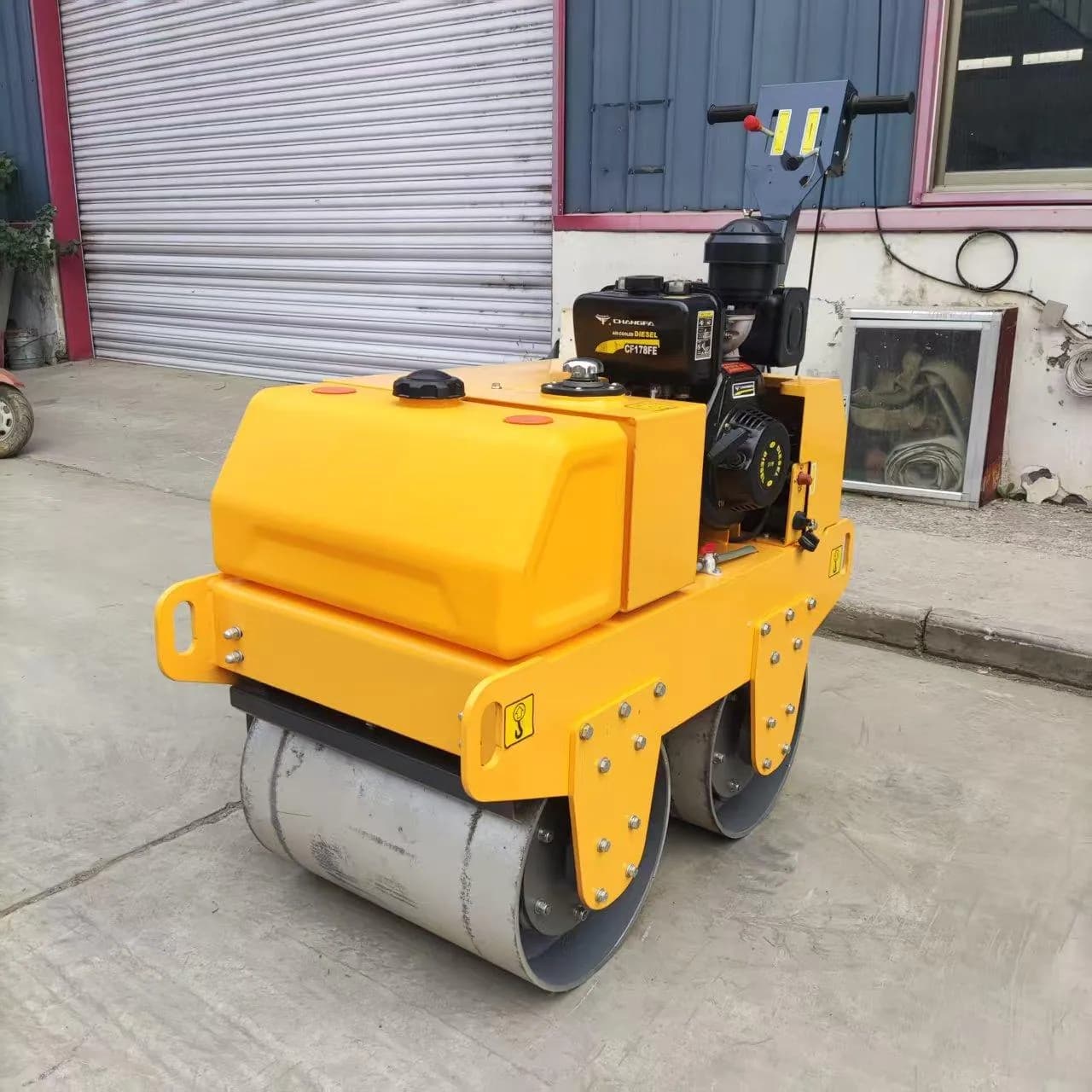 Yellow walk-behind twin-drum roller with long handle, front three-quarter view