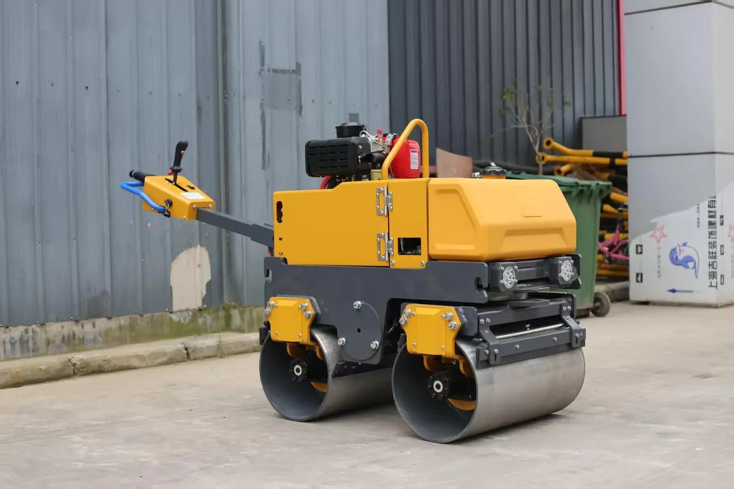 Yellow walk-behind roller showing both steel drums, side-front view