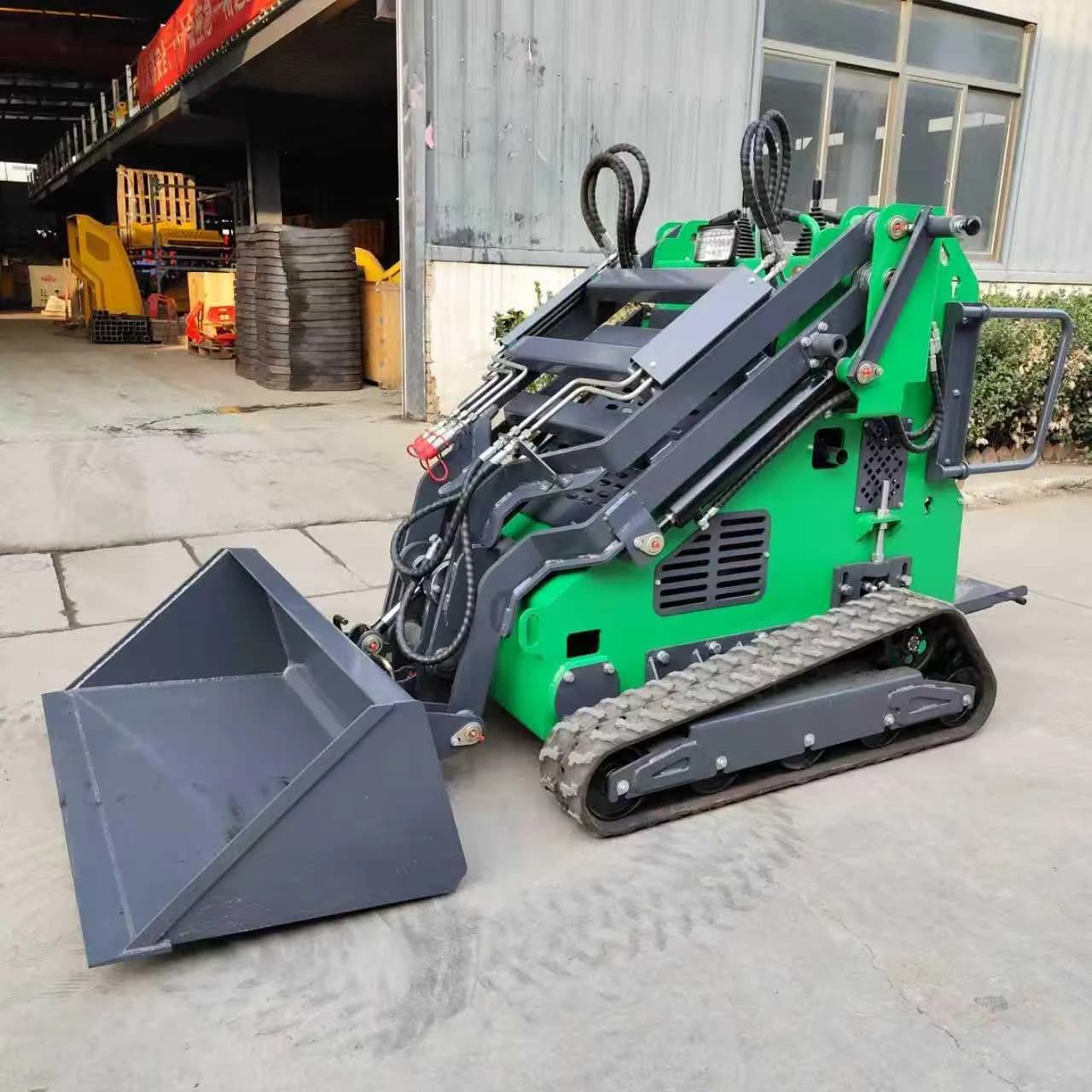 Green tracked stand-on loader with lowered bucket and visible hydraulic lines