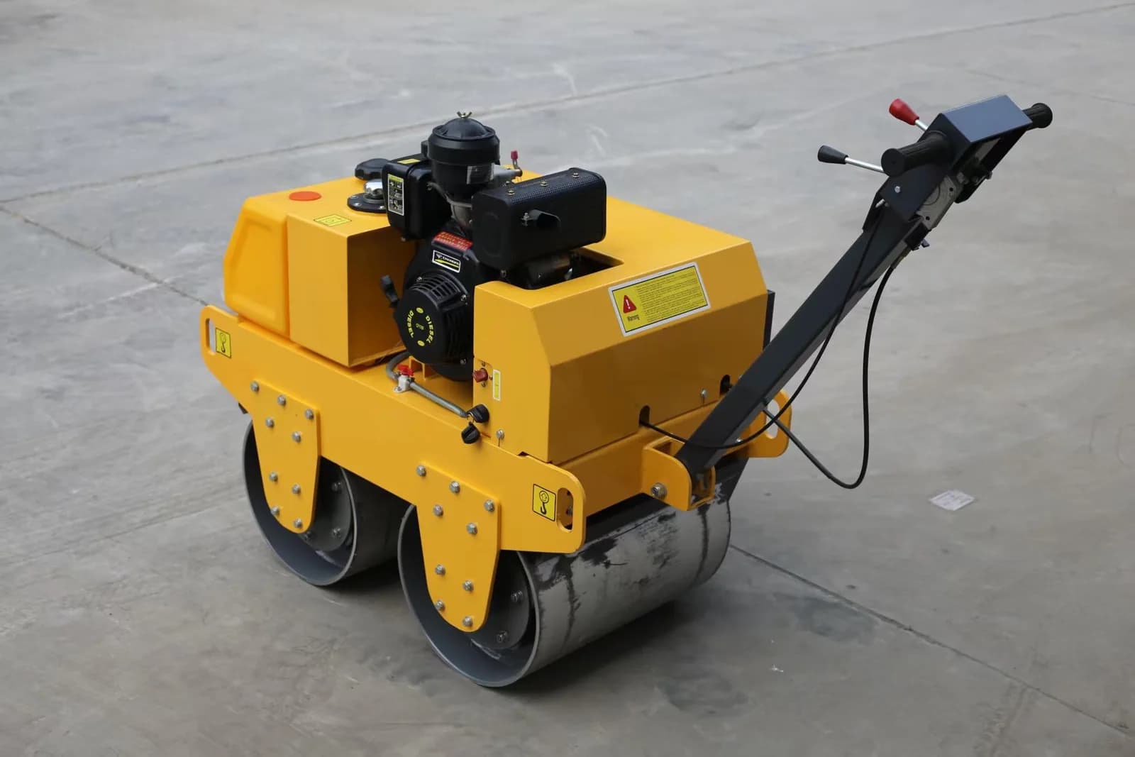 Walk-behind road roller with drums, engine and long handle