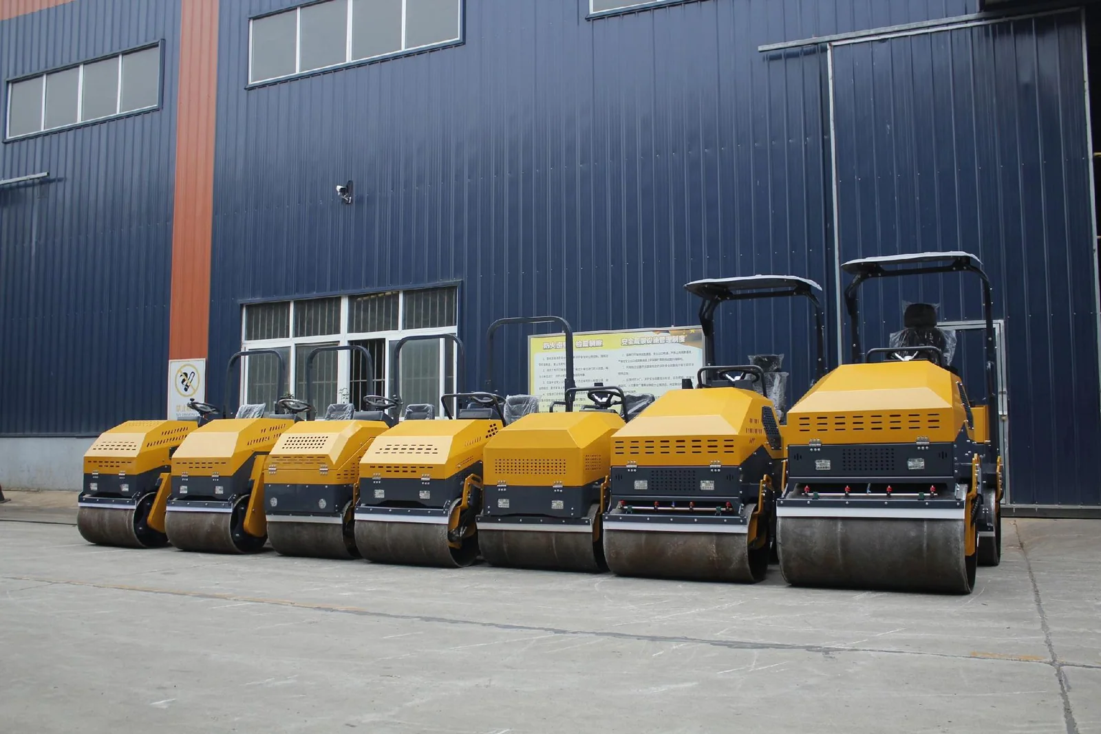 A lineup of ride-on road rollers with canopies and steel drums